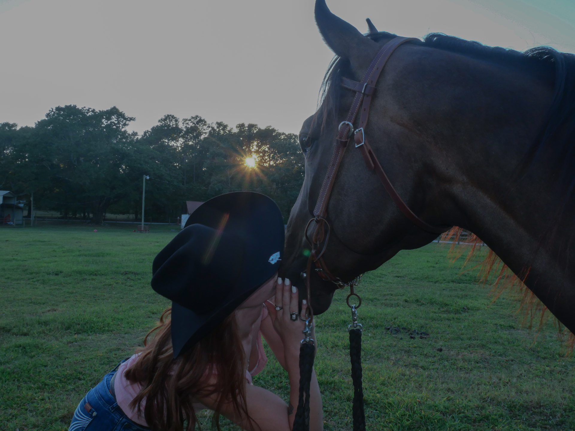 A leather western saddle resting on a weathered wooden fence at golden hour